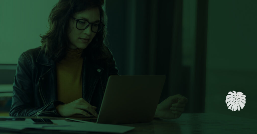 A Hispanic communications professional working on a laptop in an office, representing how school districts use AI translation for multilingual communication.