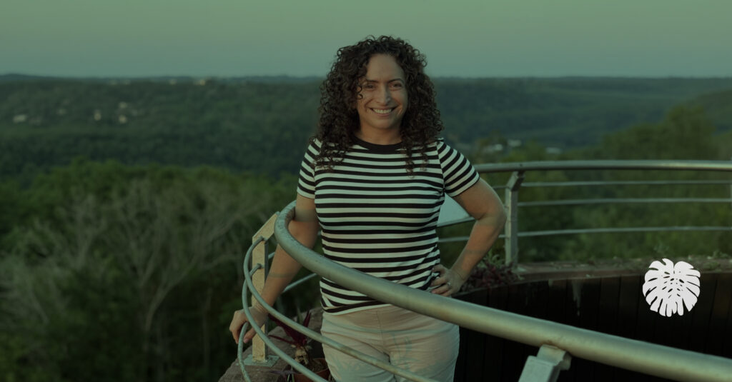 Micaela Novas, founder of The Translation Team, smiling outdoors with a green landscape in the background.